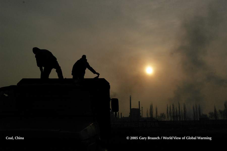 Men work in late afternoon unloading coal at yard near Baotou, Inner Mongolia, China, where nearby coal mines serve giant powerplants.