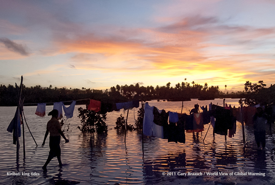 Girls wade out to get laundry before higher tides reach the clothes, North Tarawa, Kiribati, during King tides, 2011. See Islands.