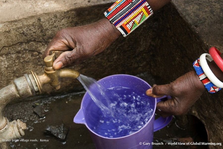 Woman fills pail with water harvested from village roofs near Nairobi Kenya, adaptation, solution to drought. 