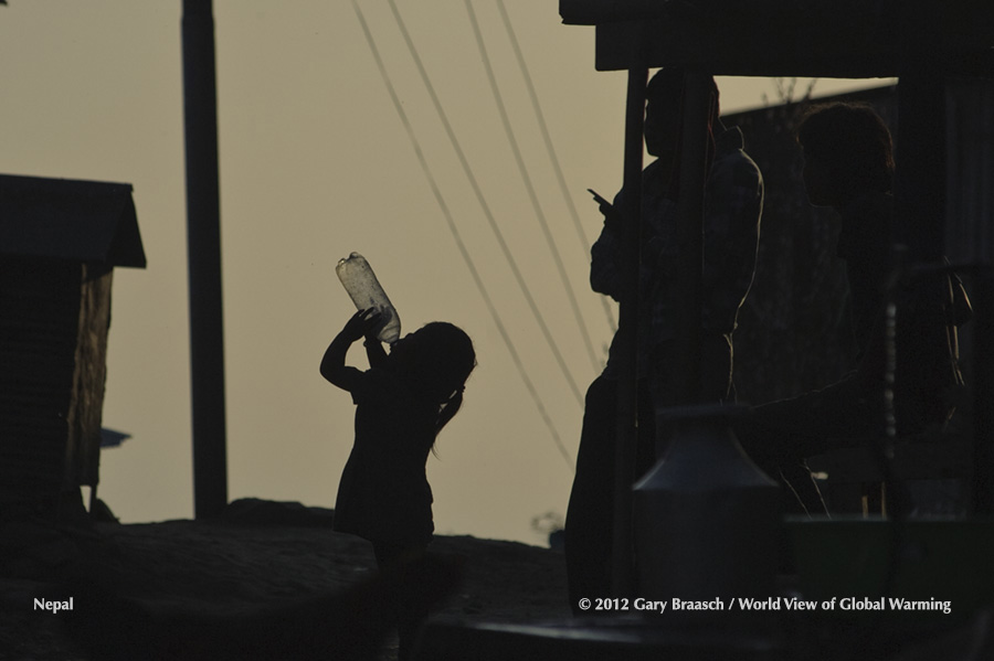 Nepalese girl drinks from discarded plastic bottle to get last drop of water. Pure water increasingly scarce in Nepal. See Himalaya. See Drought.